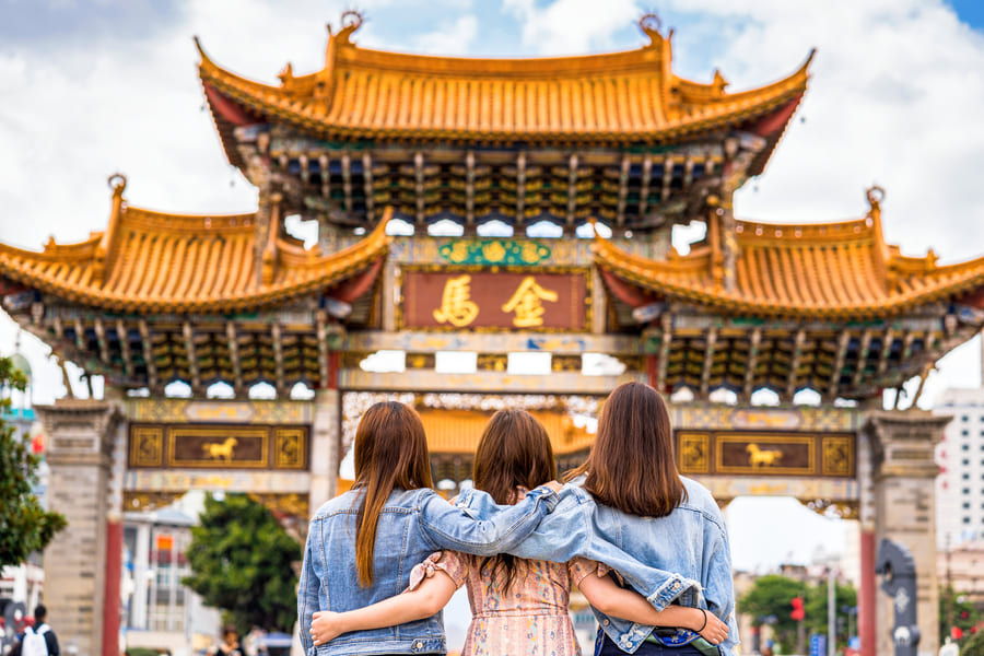 Templo de China al fondo con tres turistas observando mientras se abrazan